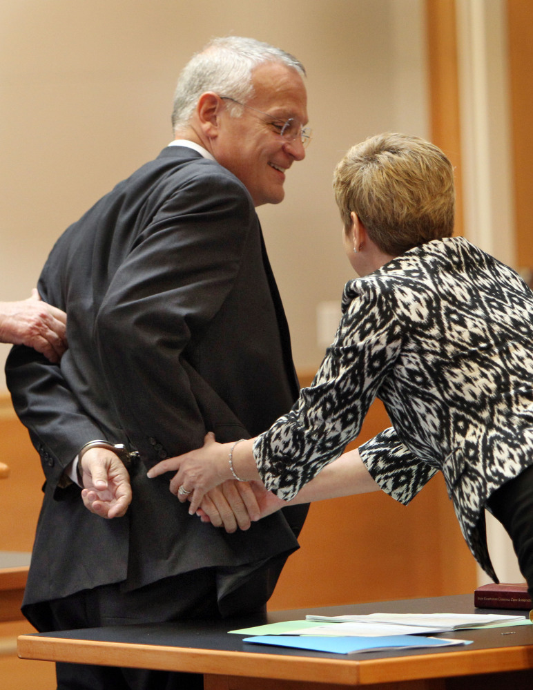 Monsignor Edward Arsenault reaches out with his handcuffed hand to shake hands with prosecutor Jane Young after pleading guilty to three felony theft charges in Hillsborough County Superior Court in Manchester, N.H., on Wednesday.