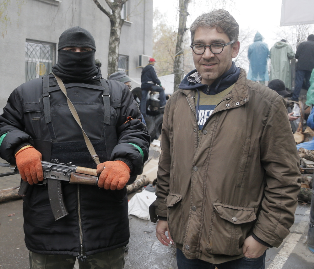 U.S. reporter Simon Ostrovsky stands with a Pro-Russian gunman at a seized police station in the eastern Ukraine town of Slovyansk on April 13. Gunmen admitted Wednesday that they are holding Ostrovsky captive.