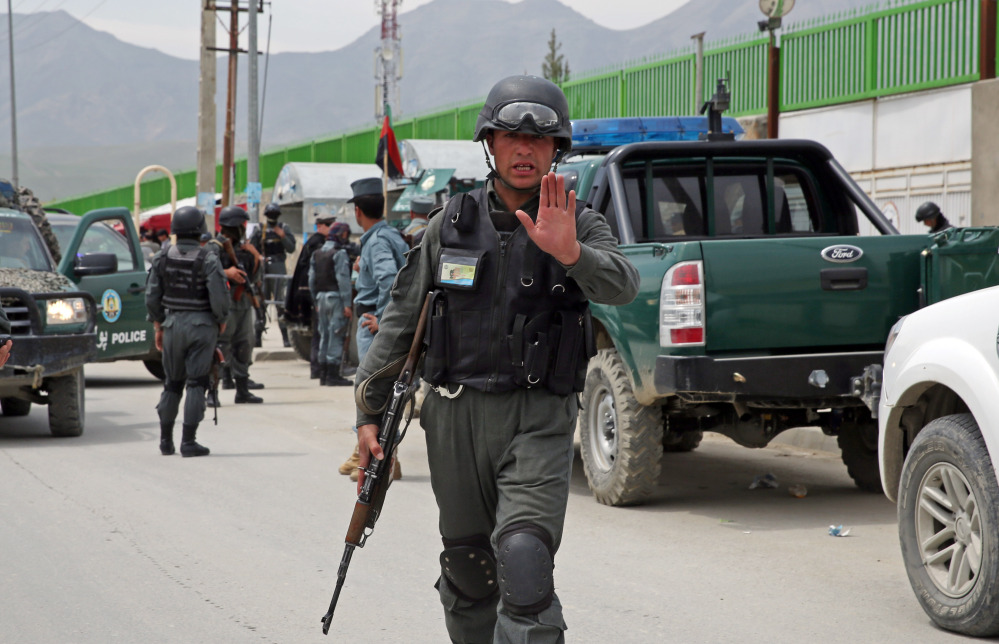 An Afghan policeman prevents journalists from approaching Cure International Hospital in Kabul, Afghanistan, Thursday.