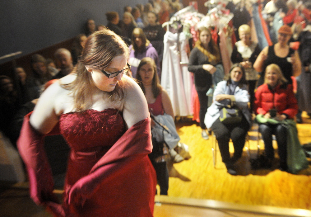 Ready in red: Cassandra Crawford, 18, of Wiscasset, displays a dress from the stage Saturday at Johnson Hall in Gardiner during the Cinderella Project. More than 100 teenage girls converged on Johnson Hall to pick up donated dresses, shoes and jewelry.
