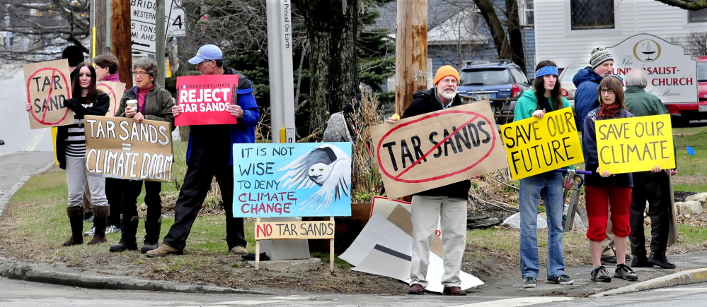 PROTEST: Carrying posters showing their opposition to tar sands oil and the proposed Keystone XL pipeline, about a dozen people, including Richard Thomas, center, and Iver Lofving, facing at right, make their point Sunday outside the Universalist/Unitarian church in Waterville. The group, which has protested weekly, now plans to do so only once per month.