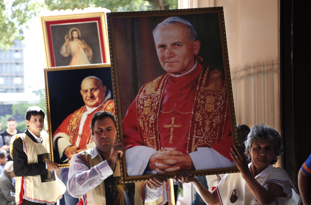 Catholics at “La Encarnacion” church in Asuncion, Paraguay, hold posters of Popes John Paul II, right, and John XXIII to celebrate the historic day, with Popes Francis and Benedict XVI honoring John XXIII and John Paul II.
