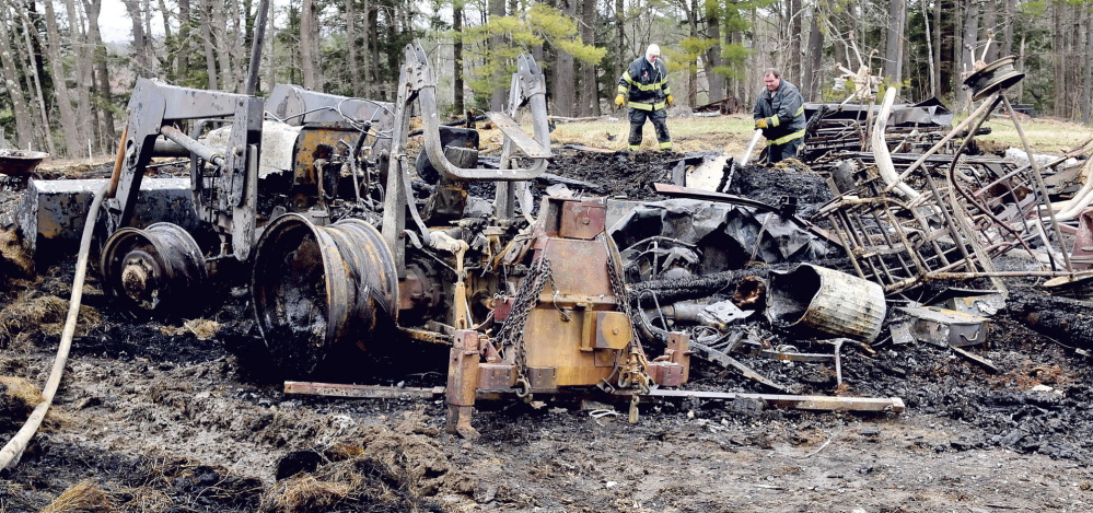 FATAL FIRE: Norridgewock firefighters James Gordon, left, and Ryan Jones hose down hot spots in the burned remains of a barn on Elm Street in Mercer on Monday, April 28, 2014. Owner Jason Hilton said the fire started in the early morning and believes the cause is electrical. A horse and three goats died and farm equipment was destroyed.