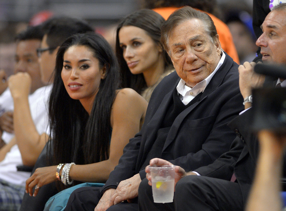 Los Angeles Clippers owner Donald Sterling, right, and V. Stiviano, left, watch the Clippers play the Sacramento Kings in Los Angeles on Oct. 25, 2013.