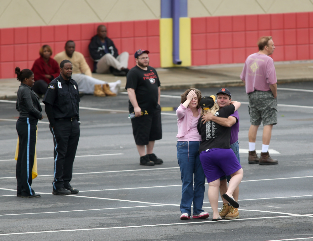 A FedEx employee, facing, is consoled after an early morning shooting Tuesday in Kennesaw, Ga.