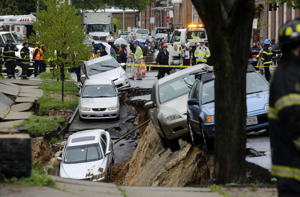Cars sit on the edge of a sinkhole in Baltimore on Wednesday as heavy rain moves through the region.