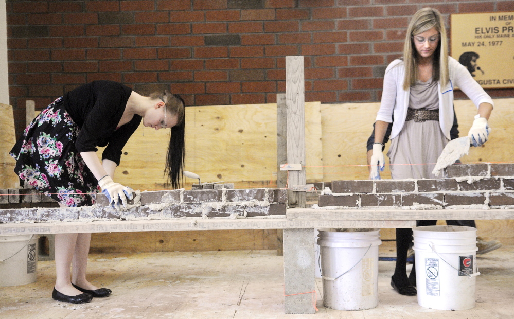 GETTING AWAY WITH MORTAR: Waterville High School student Destiny Petit, left, and Madison Area Memorial High School student Gretchen Miller assemble a brick wall Wednesday during the annual Jobs for Maine’s Graduates Career Development Conference in Augusta. The daylong conference introduced JMG students to a variety skills and employers, including the Maine Masonry Co.