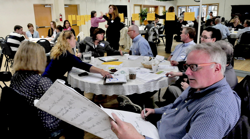 SOLUTIONS: Multiple agencies, including a group from Kennebec Behavior Services, in foreground, met on Wednesday to discuss solutions to youth homelessness. Ideas for dealing with the problem were posted on a wall, in the background, and later prioritized by the groups.