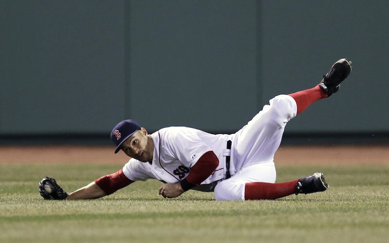 Boston Red Sox center fielder Grady Sizemore rolls as he makes the catch on a sacrifice fly by Texas Ranger Mitch Moreland, which scored Adrian Beltre, during the fourth inning of a MLB baseball game at Fenway Park, Monday, April 7, 2014, in Boston.