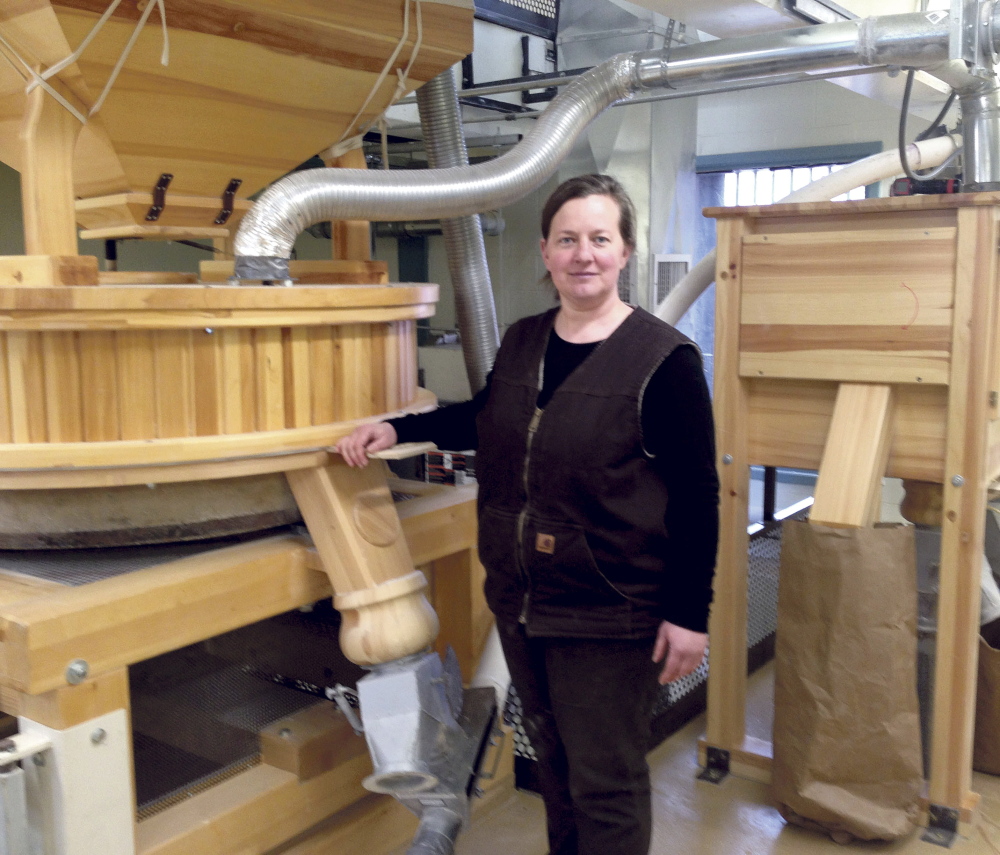 GOING PLACES: Amber Lambke stands beside a working mill grinding flour at the Somerset Grist Mill in Skowhegan on Wednesday. Lambke, president of Maine Grains, will travel this summer to Iceland as part of a trade mission.