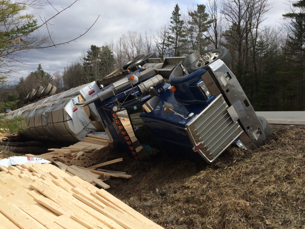 On its side: A tractor-trailer truck rests on its side Monday morning on U.S. Route 201 in Solon. The driver wasn’t hurt when the truck, carrying lumber and owned by a Quebec company, caught mud at the side of the road, causing it to tip.
