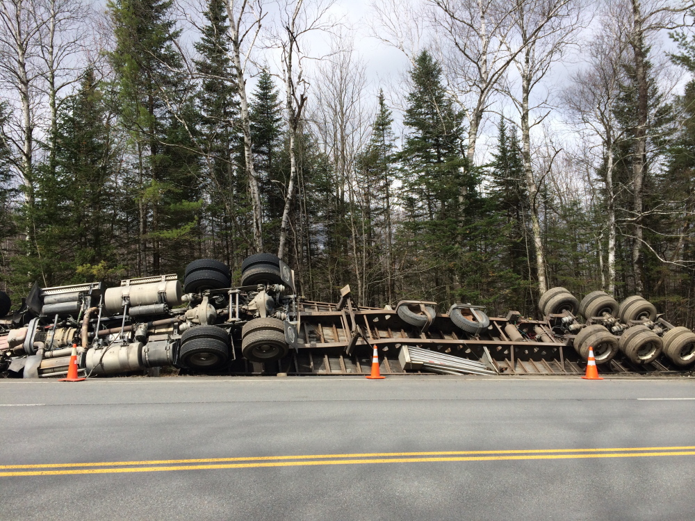 On its side: A tractor-trailer truck rests on its side Monday morning on U.S. Route 201 in Solon. The driver wasn’t hurt when the truck, carrying lumber and owned by a Quebec company, caught mud at the side of the road, causing it to tip.