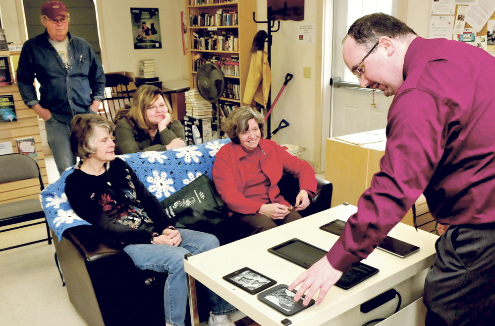 READ ON: Jared Leadbetter of the Maine State Library sets out e-readers and mobile devices during a presentation on accessing e-books at the Norridgewock Public Library on Tuesday. Taking part in the presentation are patrons from left, Merle Lewis, Dawn Smith, Kelly Adams and Ruth Keister.