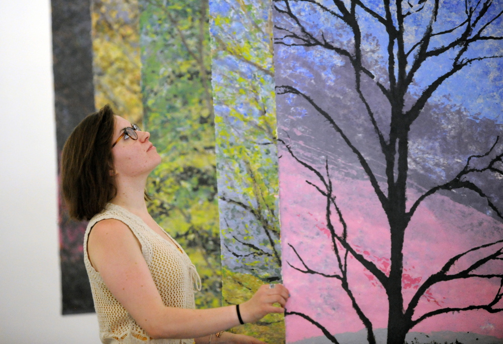 NEW EXHIBIT: Rachel McDonald, program manager at Common Street Art Gallery, arranges paintings by Readfield artist Christine Higgins at Common Street Art Gallery in downtown Waterville on Wednesday.