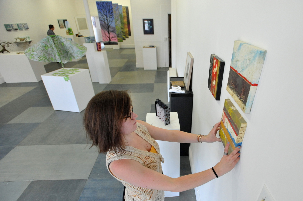 LOCAL ART: Rachel McDonald, program manager at Common Street Art Gallery, hangs pieces by Readfield artist Christine Higgins, at Common Street Art Gallery in downtown Waterville on Wednesday.