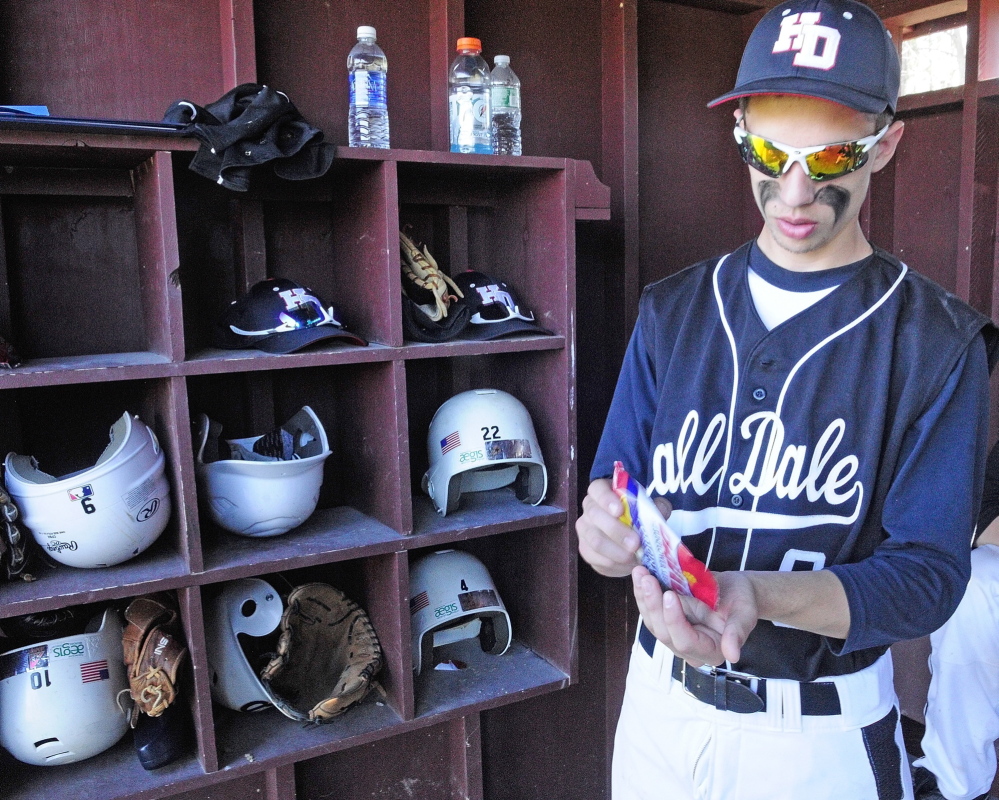 HARD HABIT TO BREAK: Hall-Dale outfielder Tyler Dubois grabs a handful of sunflower seeds before the start of a game Wednesday in Monmouth. The seeds, made in many different flavors, seem to be the snack of choice for players these days.