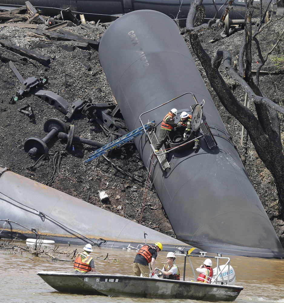 ANOTHER DERAILMENT: Workers remove damaged tanker cars along the tracks where several CSX tanker cars carrying crude oil derailed and caught fire along the James River near downtown Lynchburg, Va., on May 1.