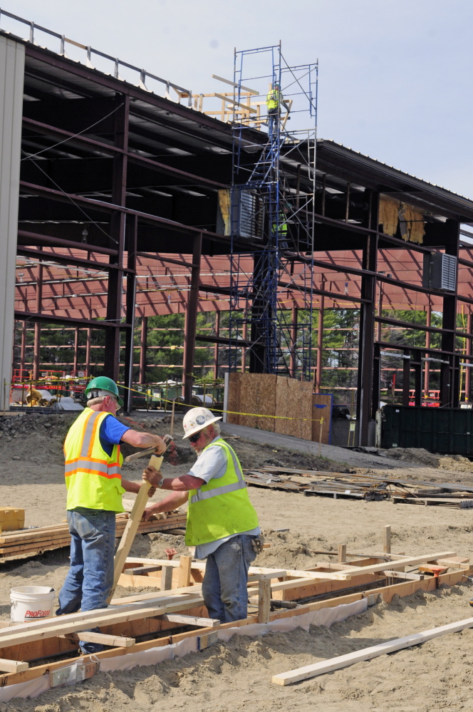TRANSPORTATION MOVE: The state’s future fleet maintenance site at 66 Industrial Drive, where workers in the foreground are building forms for an addition where trucks can be painted and workers in the background on scaffolding remove the roof from the former warehouse on the site.