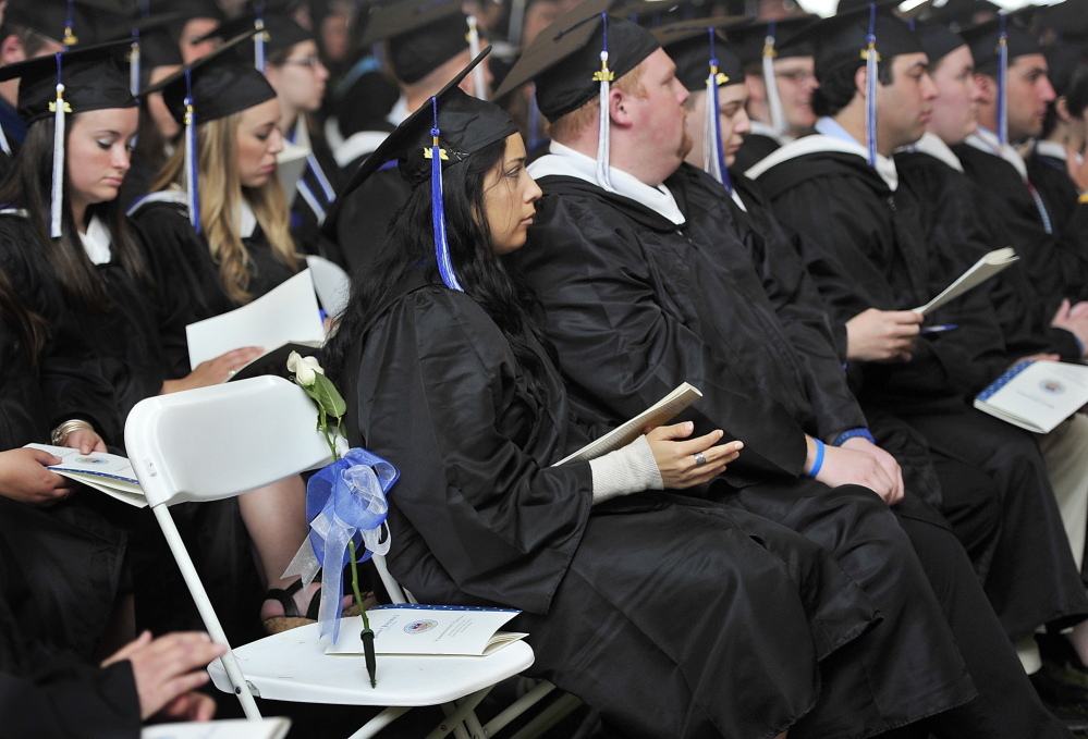 A single white rose tied with a blue ribbon rests on an empty chair during the Saint Joseph’s College graduation in Standish. The rose honors the memory of Clark Noonan, a basketball player who died in a car crash in April 2012.