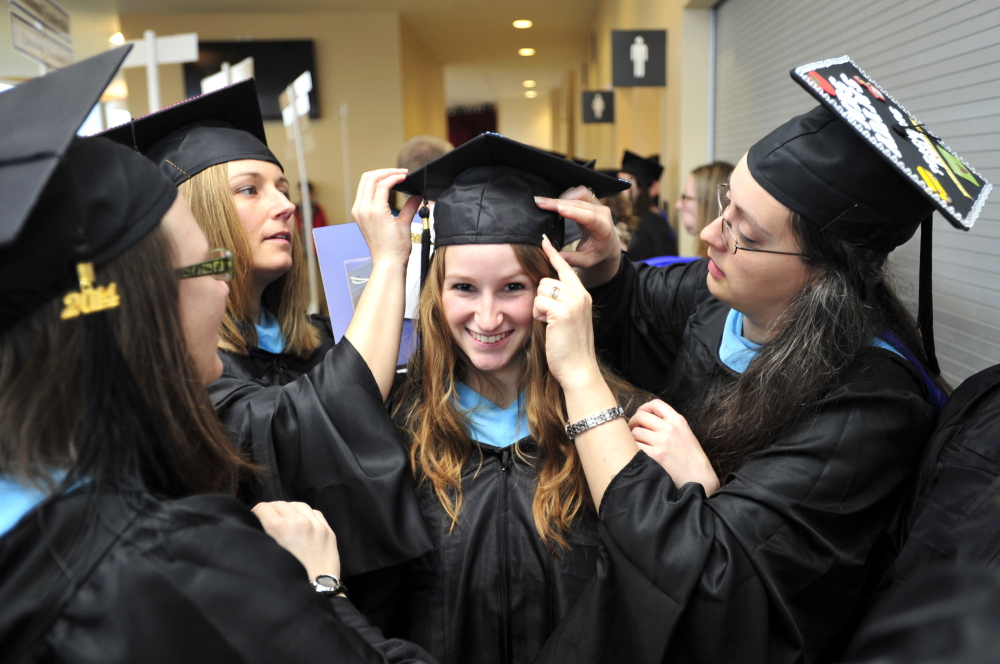 Sarah Quint, center, of Wells gets her cap securely pinned to her hair by fellow graduates Krista Chamberlain of Buxton, second from left, and Melissa Adams of Biddeford, right, as they get ready for the USM graduation procession at Cumberland County Civic Center in Portland on Saturday. Each received a master’s degree in teaching and learning.