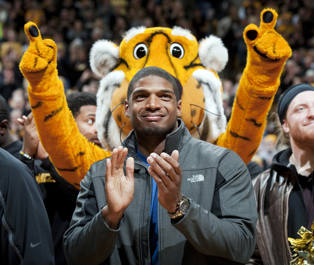 In this Feb. 15, 2014, file photo, Missouri’s All-American defensive end Michael Sam claps during the Cotton Bowl trophy presentation at halftime of an NCAA college basketball game between Missouri and Tennessee in Columbia, Mo.