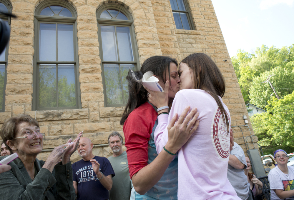 Jennifer Rambo, right, kisses her partner Kristin Seaton following their marriage ceremony in front of the Carroll County Courthouse in Eureka Springs, Ark., on Saturday. Sheryl Maples, far left, the lead attorney who filed the Wright v. the State of Arkansas lawsuit, is at left.