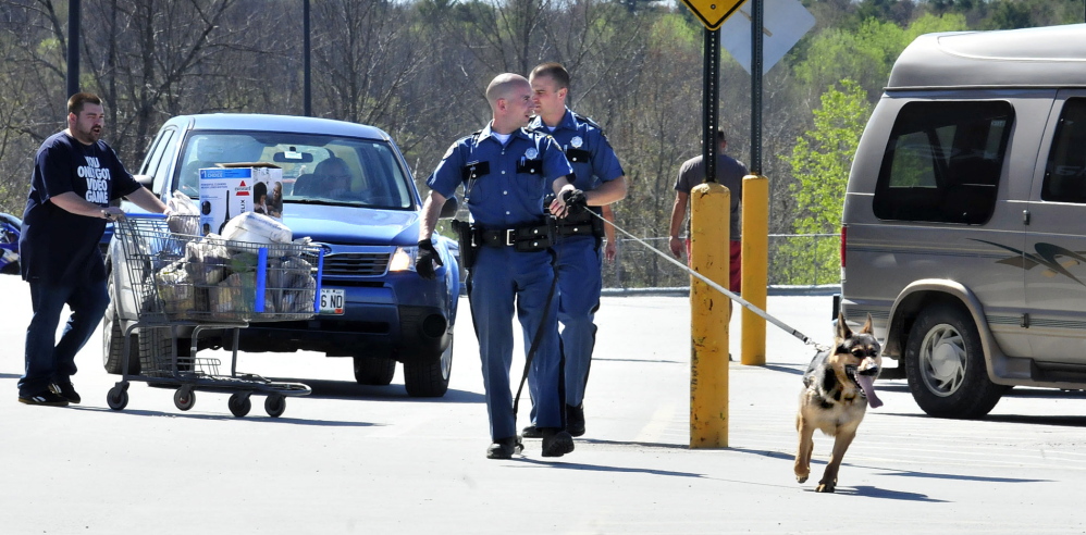 SEARCHING: Two state troopers and a tracking dog search vehicles in the Walmart parking lot after two people said they were robbed while making a deposit at the nearby Bangor Savings Bank in Waterville on Sunday, May 11, 2014.