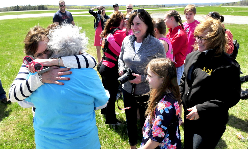WELL DONE MA: Marjorie Bell, 80, is hugged by one of her daughters, Norma Thompson, after Bell safely landed after tandem skydiving at Lafleur airport in Waterville on Sunday, May 11, 2014. Waiting to congratulate their mother are daughters Mary Therriault, center, and Sheila Currie. Grandaughter Maggee Currie is in front.