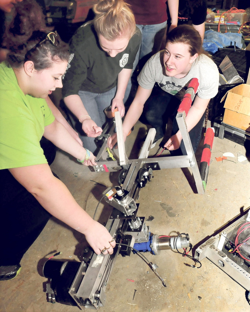 BRIGHT FUTURES: Messalonskee High School Robotics team members make repairs to the claw of the team’s robot, which competed in the national championship in St. Louis. From left are Sydney O’Neal, Dakota Condon and Gretchen Rice.