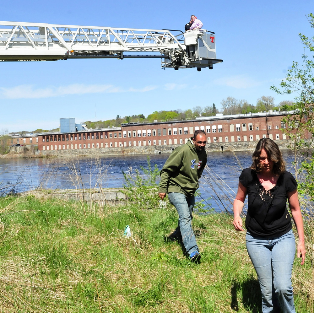 REUNITED: Joe Bradley and Darlene Champagne move as Waterville firefighter Mark Hamilton brings Mary Temple back to the ground in a department ladder truck bucket Tuesday after rescuing her from a granite abutment beside the Kennebec River at Head of Falls in Waterville. Temple said she feared climbing down the steep structure.