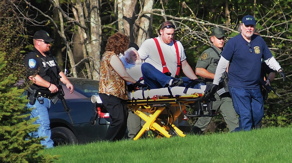 Walter Nolan, father of Michael Nolan, is escorted by police officers as he is taken on a stretcher from his home in Brentwood, N.H., on Monday. Michael Nolan is believed to have killed a police officer before setting the house afire and dying in the blaze.