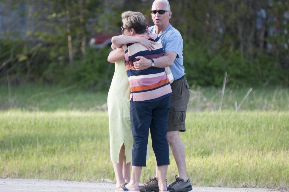 Neighborhood residents embrace after a police officer was fatally wounded at a home in Brentwood, N.H., on Monday.
