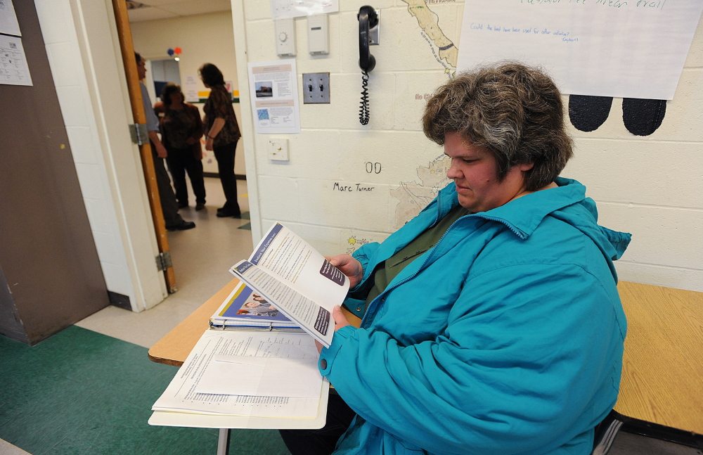 FACING UNEMPLOYMENT: United Technologies employee Darlene Chamberlain of Pittsfield reads a booklet on how to take steps to financial sucess while waiting with other job seekers at a career workshop during a job fair in Pittsfield on Wednesday. Chamberlain will lose her job when UTC closes.