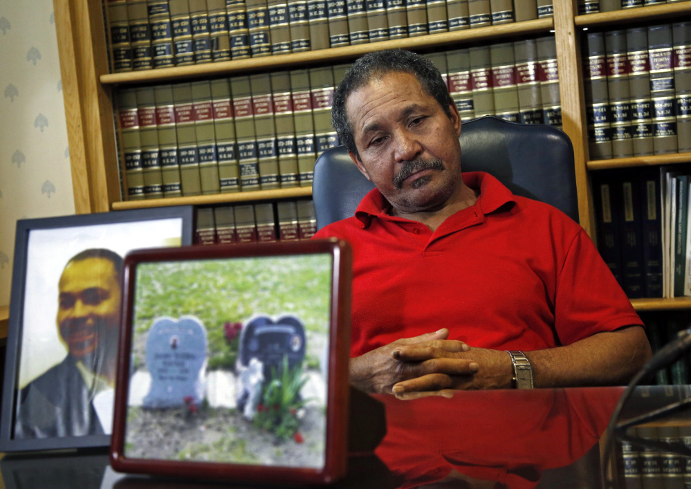 Ernesto Abreu listens during a news conference at his attorney’s office in Quincy, Mass., Thursday, May 15, 2014, with photos of his son, Daniel de Abreu, and the gravesite of Daniel and Safiro Furtado. Daniel and Safiro were shot to death as they sat in a car in Boston’s South End on July 16, 2012. Former Patriots star Aaron Hernandez has been indicted Thursday on new murder charges in this 2012 double slaying.