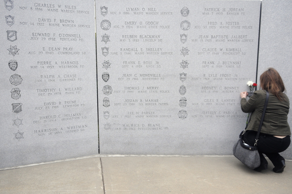 Remembered: Cherrie Bonney tapes flowers next to the name of her husband, Rodney Bonney, inscribed on the Maine Law Enforcement Officers Memorial during a service Thursday in Augusta. Auburn Police Officer Rodney Bonney drowned April 6, 1981, attempting to save a teenage boy who fell into the Androscoggin River.