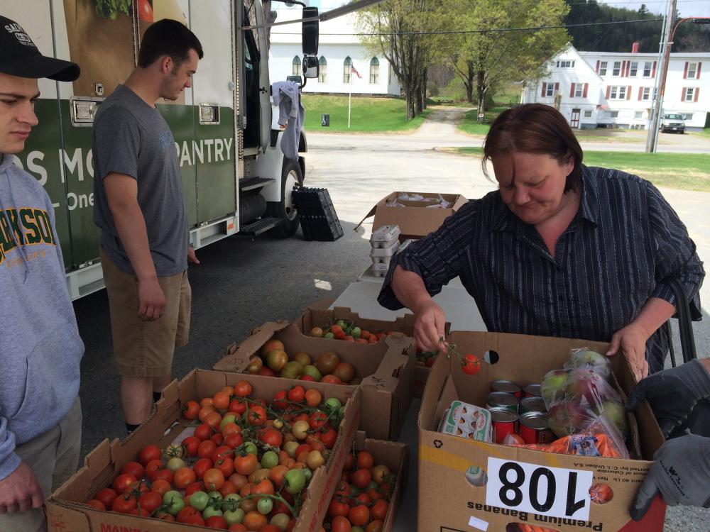 FRESH FOOD: Julie Bradley, 51, of Moscow, picks up some fresh tomatoes from the Good Shepherd Food Bank Mobile Food Pantry on Friday in Bingham, while volunteer Calvin Stewart, 18, watches.