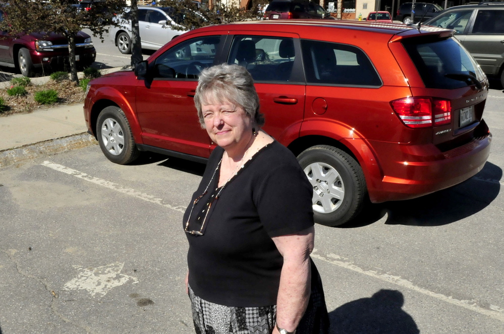 CONCERN: Faye Nicholson, co-executive director of REM in Waterville, stands beside a parking spot marked with a star for all-day parking in The Concourse. Nicholson thinks Waterville’s farmers market, which occupies part of the parking lot on Thursdays, would better serve shoppers and people who need parking spaces if it were moved to nearby Head of Falls along the Kennebec River.