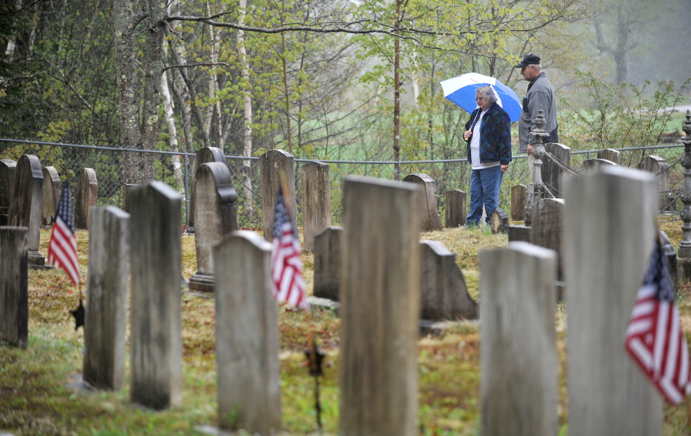 Communing with the past: Elsie Bonney and her husband, Larry Bonney, of Bethel, browse among the various headstones Saturday at Frederic Cemetery in Starks. The Maine Old Cemetery Association, which works to preserve old cemeteries, held its annual spring meeting in Starks.