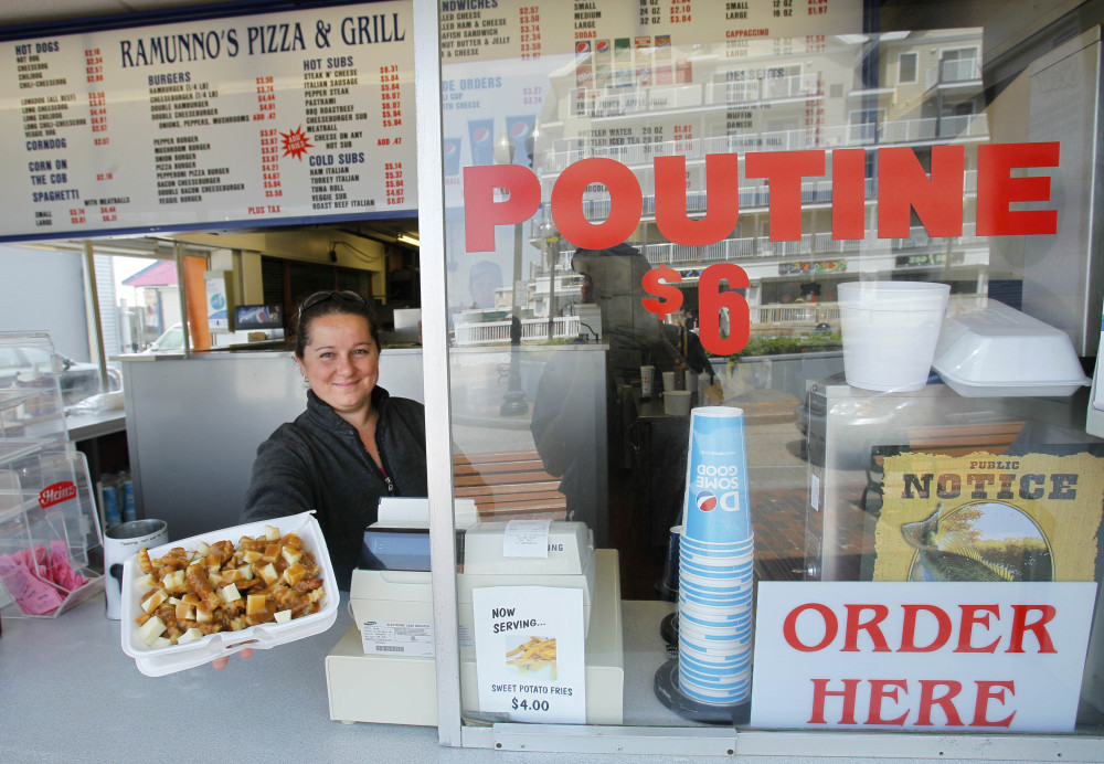Karen Ramunno of Ramunno’s Pizza and Grill delivers an order of poutine, a french fry, gravy and cheese dish popular with Canadians, in Old Orchard Beach. Poutine is one of the 150 new words appearing in Merriam-Webster’s Collegiate Dictionary and the company’s free online database.