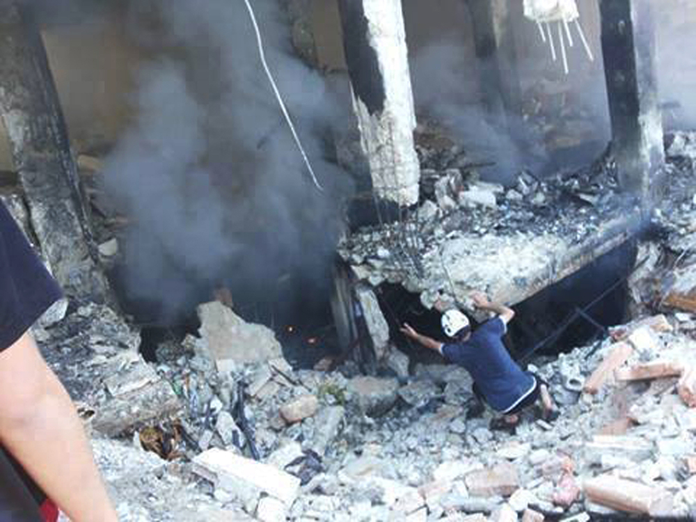 This photo provided by an anti-Bashar Assad activist group Edlib News Network (ENN), which has been authenticated based on its contents and other AP reporting, shows a Syrian man checking a damaged building at the scene where a car bomb exploded outside a mosque at Binnish town, in Idlib province, northern Syria, Friday.