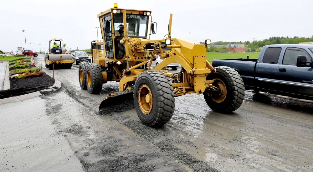 ROAD RAGE: Motorists drive around workers operating a grader and roller resurfacing Waterville Commons Drive Monday. Road conditions and heavy traffic last Saturday contributed to major congestion, causing delays and road rage.