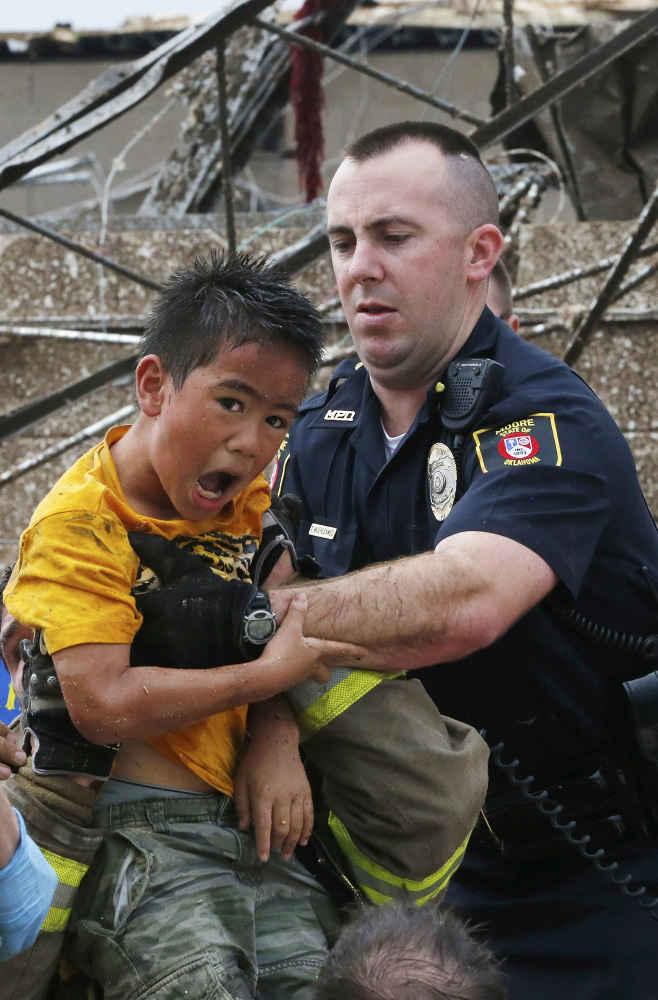 Kai Heuangpraseuth, left, is pulled from beneath a collapsed wall at the Plaza Towers Elementary School after a tornado on May 20, 2013, in Moore, Okla. Heuangpraseuth will return to a new Plaza Towers Elementary in the fall, built on the same spot where seven of his schoolmates died.