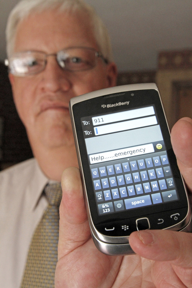 In this April 18, 2012, file photo, David Tucker, executive director of Vermont’s Enhanced 911 Board, holds a smart phone in Montpelier, Vt. Tucker says the state is the first in the country where customers of the four major wireless carriers can send text messages to 911.