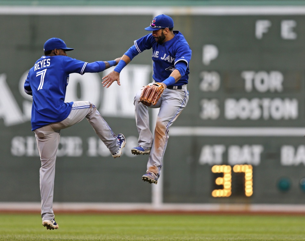 Toronto Blue Jays right fielder Jose Bautista, right, leaps as his celebrates with teammate Jose Reyes after the Blue Jays defeated the Boston Red Sox in a baseball game at Fenway Park, Thursday, May 22, 2014, in Boston. Bautista went 3-for-5 with two RBIs in the Blue Jays’ 7-2 win.