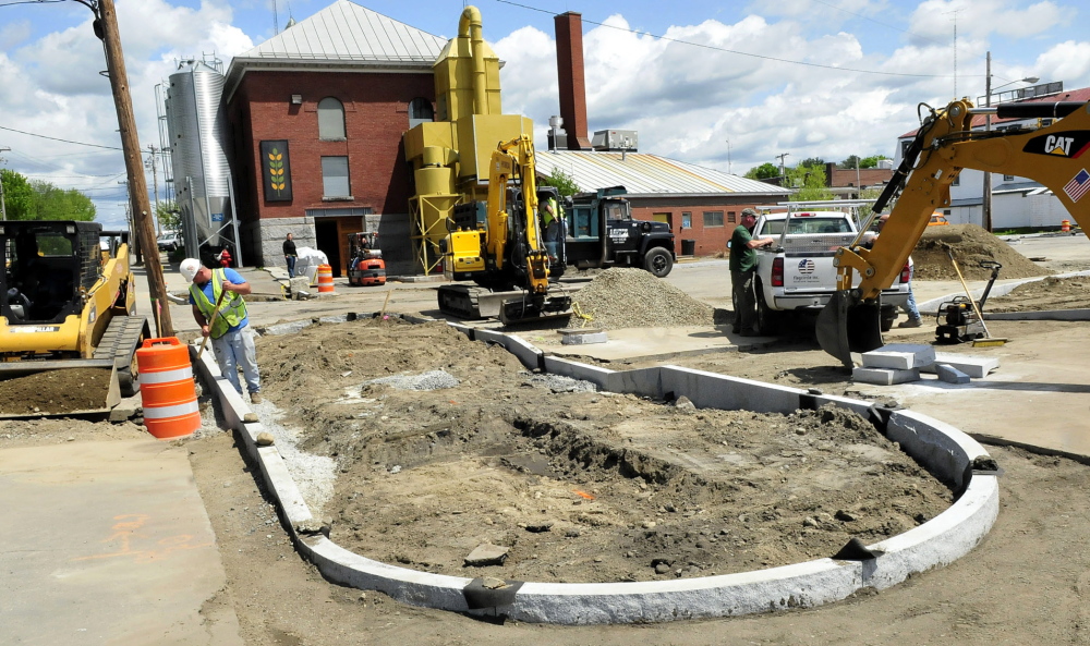 PROGRESS: Workers install granite sidewalk sections and prepare to resurface the parking lot Thursday near the Somerset Grist Mill in Skowhegan as part of a $400,000 grant paying for upgrading the municipal parking lot.