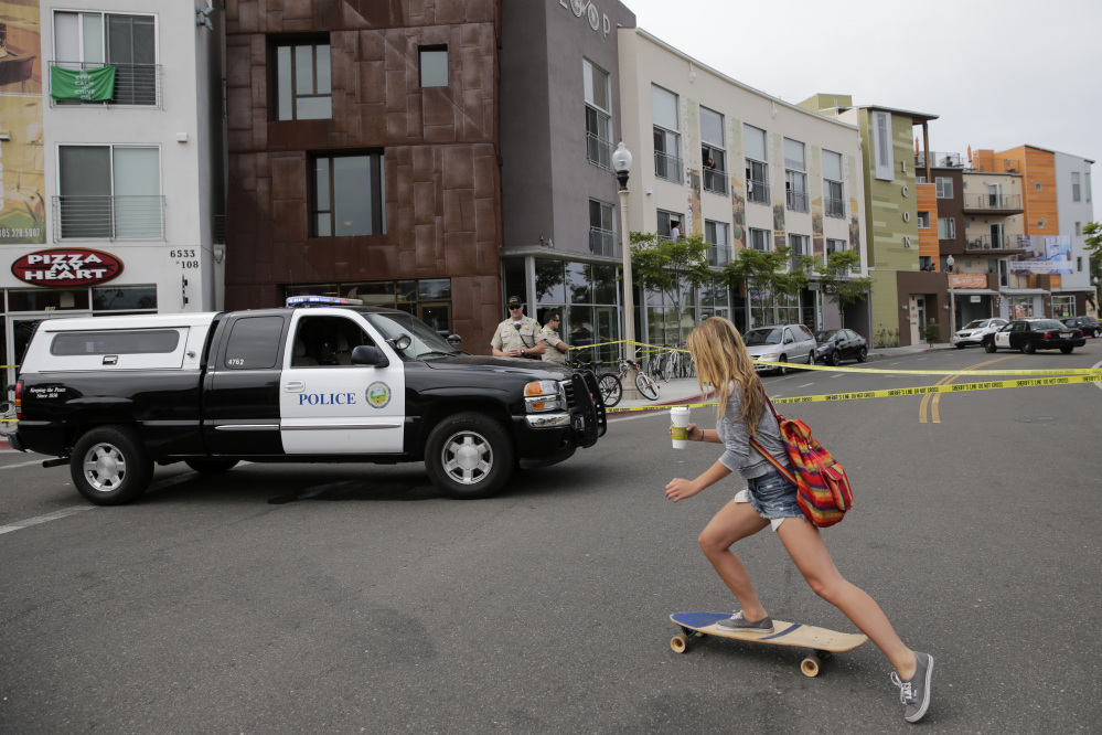A woman rides her skateboard past the scene of a shooting on Saturday in Isla Vista, Calif. A drive-by shooter went on a rampage near a Santa Barbara university campus that left seven people dead, including the attacker, and others wounded, authorities said Saturday.