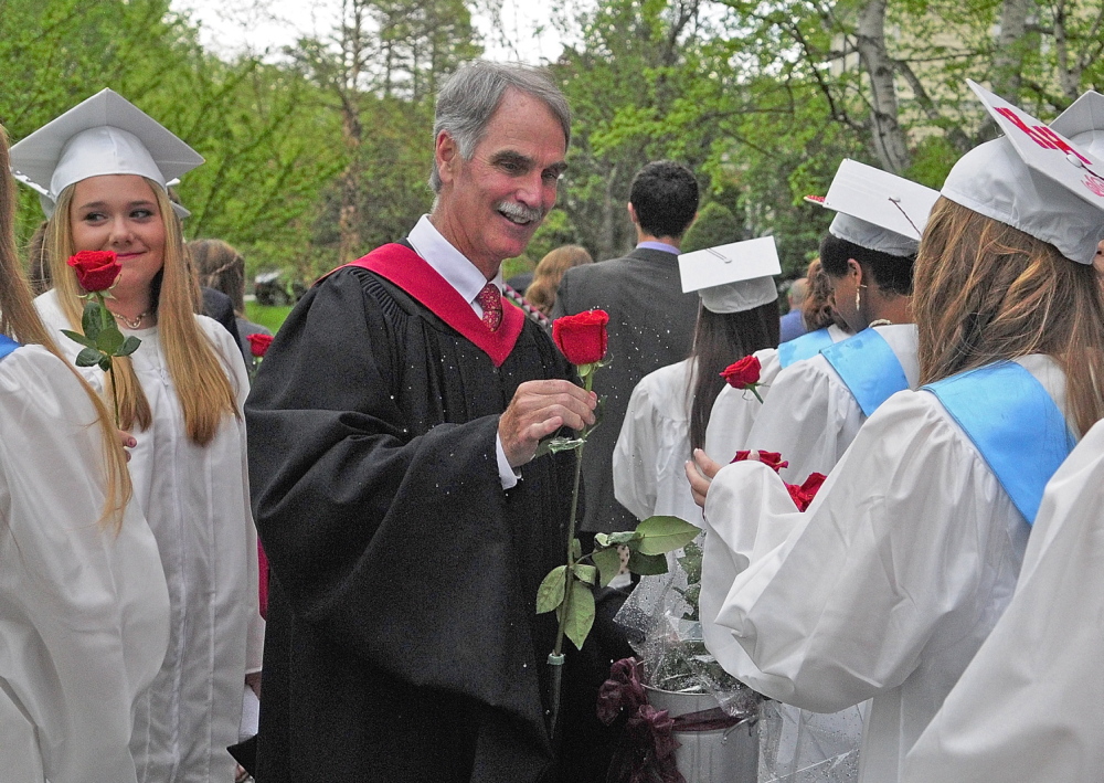THE FLOWER HOUR: Head of School Pat McInerney shakes water off a rose as he hands it to one of the female graduates before they file into graduation ceremony Saturday at Kents Hill School in Readfield.