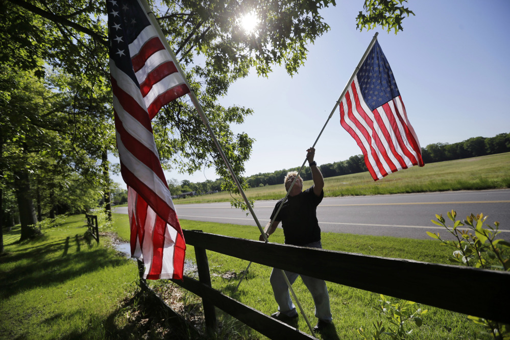 Bob Petersen places flags along a fence for the Memorial Day weekend, at his home in the Cream Ridge section of Upper Freehold, N.J., on Sunday.