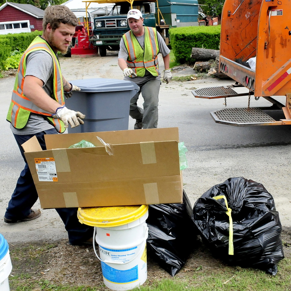 PAY UP: Waterville Public Works employees Larry Colson, left, and Brian Ames pick up city trash on Thursday, May 22, 2014. There are strong opinions on the subject of the pay-as-you-throw system the city is moving toward adopting.