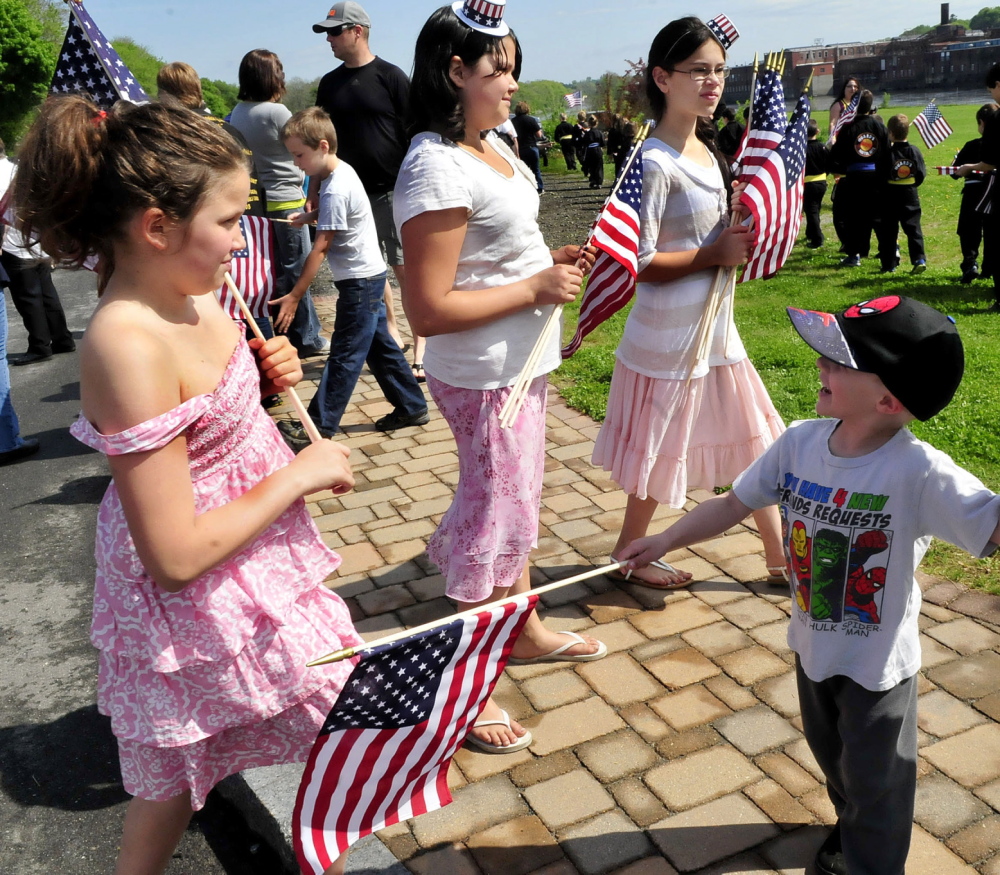Staff photo by David Leaming YOUNG PATRIOTS: These girls handed out American flags to parade marchers including Cody St. Pierre prior to the Memorial Day parade in Waterville on Monday, May 26, 2014. From left are Kaylee Levesque and sisters Aubrey and Raygen.
